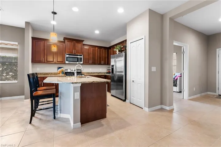 Kitchen featuring an island, appliances with stainless steel finishes, a  and light stone countertops