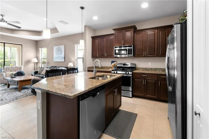 Kitchen featuring decorative light fixtures, stainless steel appliances, open floor plan, and an island with sink