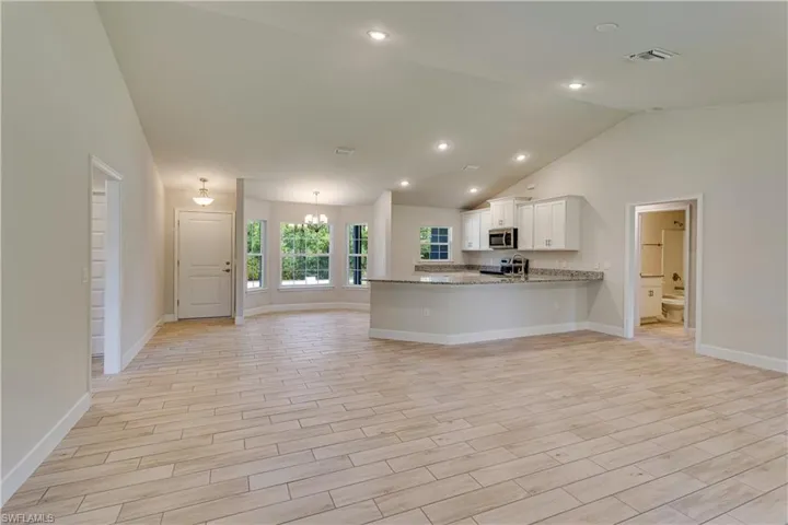 Kitchen with baseboards, stainless steel appliances, a peninsula, and white cabinetry