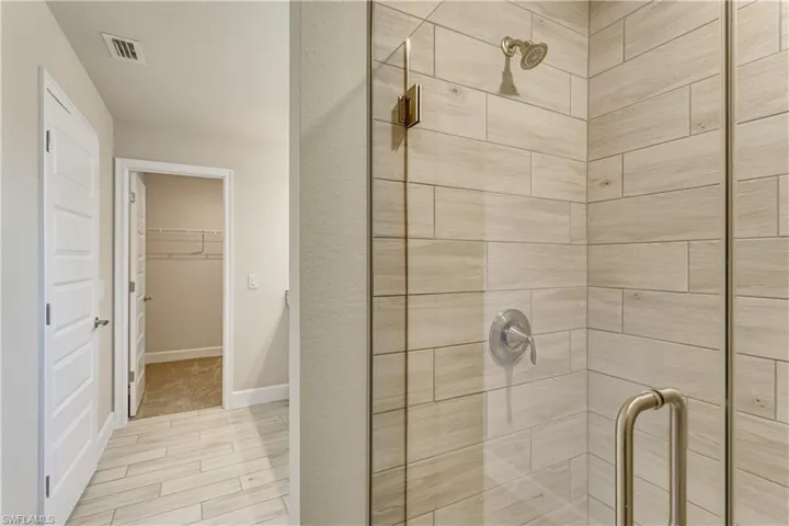 Bathroom with baseboards, visible vents, a shower stall, and a walk in closet