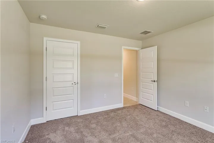 Unfurnished bedroom with visible vents, carpet, and baseboards