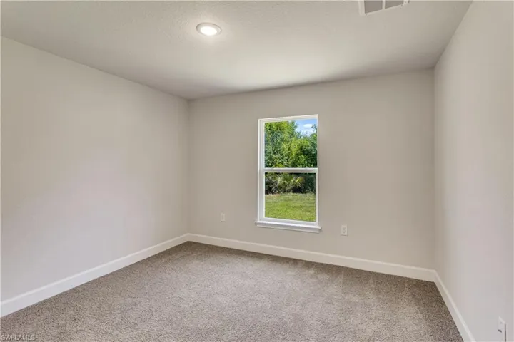 Carpeted spare room with baseboards, a textured ceiling, and visible vents