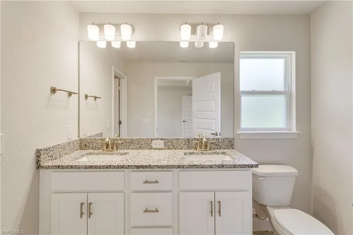 Bathroom featuring double vanity, a sink, and toilet