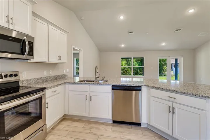 Kitchen with white cabinets, appliances with stainless steel finishes, a sink, and visible vents