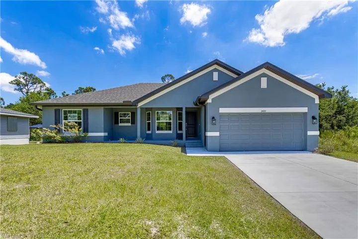 Ranch-style home featuring concrete driveway, stucco siding, an attached garage, and a front yard