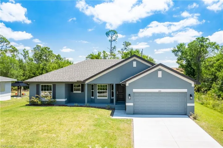 Ranch-style home featuring an attached garage, a front lawn, stucco siding, and driveway