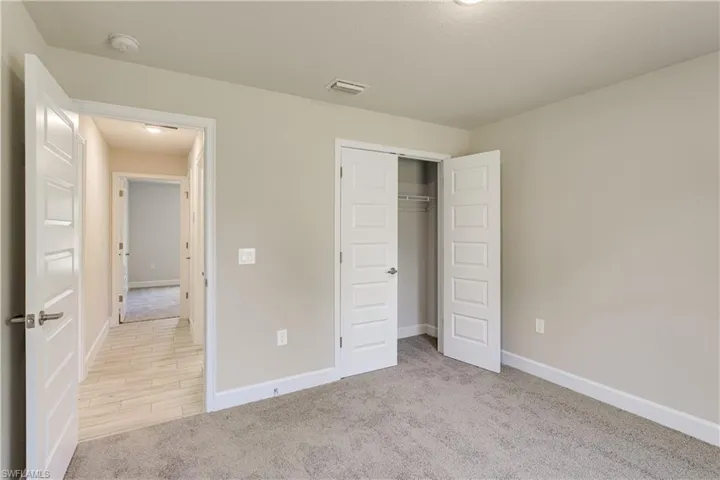 Unfurnished bedroom featuring baseboards, visible vents, a closet, and light colored carpet