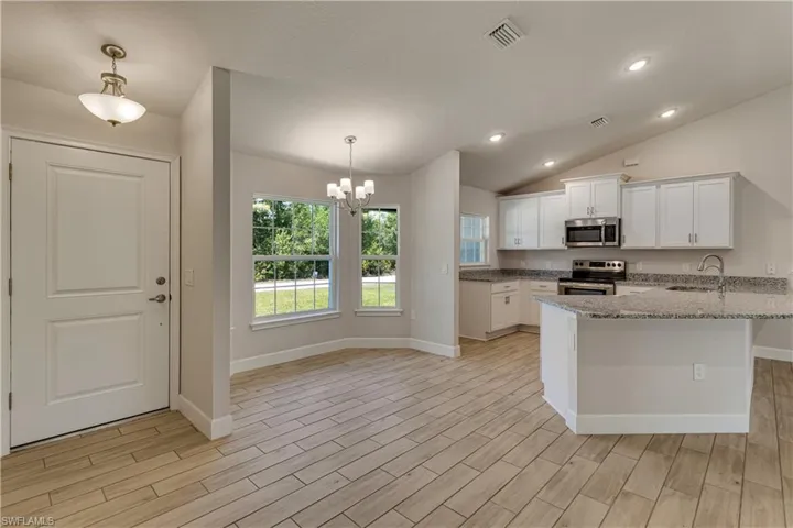 Kitchen featuring visible vents, white cabinets, a chandelier, a sink, and appliances with stainless steel finishes