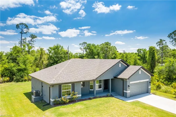 Ranch-style home with driveway, roof with shingles, a front yard, an attached garage, and stucco siding