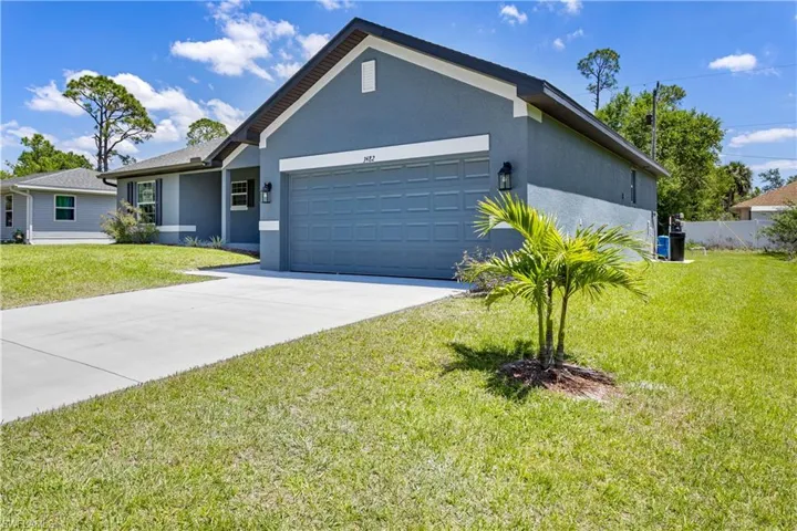 Single story home featuring an attached garage, stucco siding, driveway, and a front yard