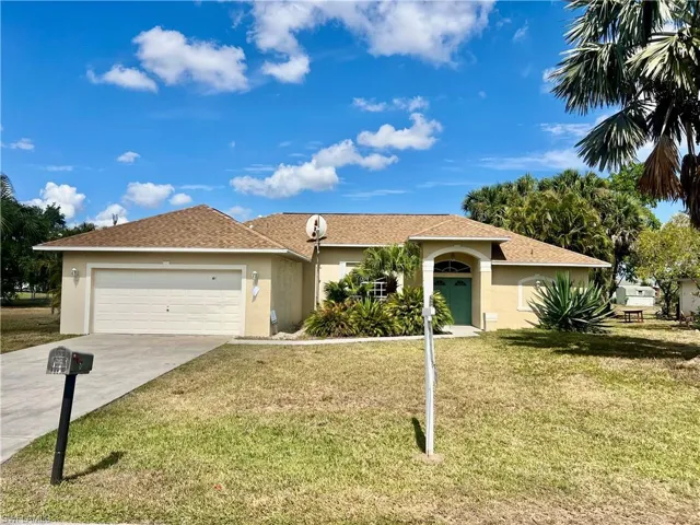 Ranch-style house featuring a garage, stucco siding, driveway, and a front yard