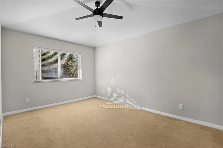 Spare room featuring carpet flooring, lofted ceiling, and a ceiling fan