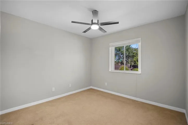 Carpeted empty room featuring baseboards and ceiling fan
