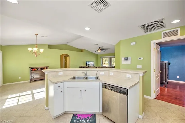 Kitchen featuring dishwasher, white cabinets, ceiling fan with notable chandelier, sink, and hanging light fixtures