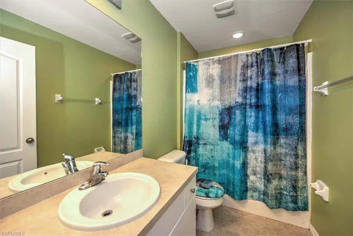 Bathroom with a shower with curtain, tile patterned flooring, vanity, and toilet