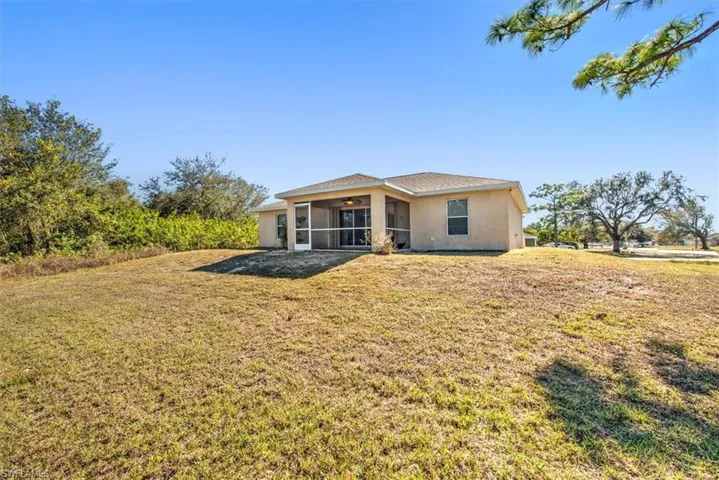 Rear view of property with a sunroom, ceiling fan, and a lawn