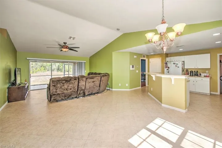 Living room featuring ceiling fan with notable chandelier and vaulted ceiling