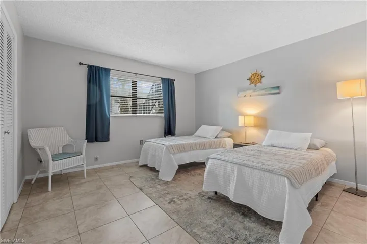 Bedroom featuring a textured ceiling, a closet, and light tile patterned floors