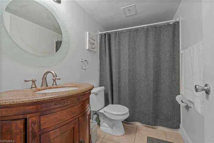 Bathroom with light tile patterned floors, curtained shower, and vanity