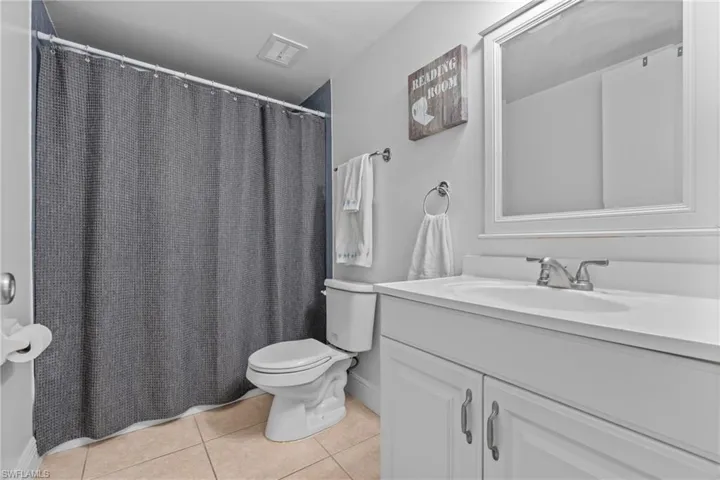 Full bath with vanity, curtained shower, and light tile patterned floors