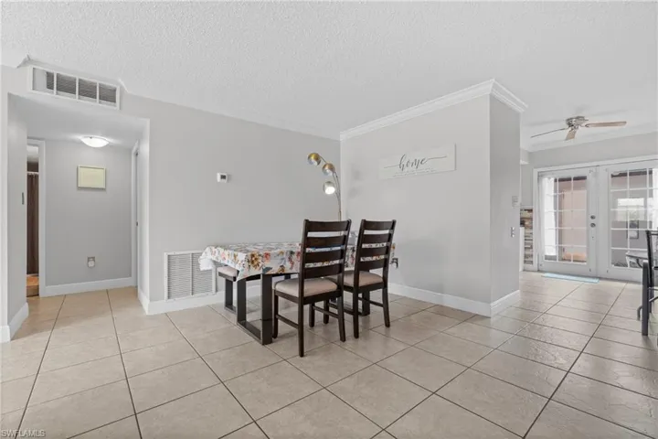 Dining room featuring ceiling fan, ornamental molding, a textured ceiling, and light tile patterned flooring