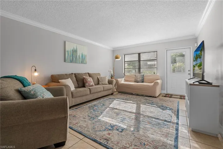 Living area featuring ornamental molding, a textured ceiling, and light tile patterned flooring
