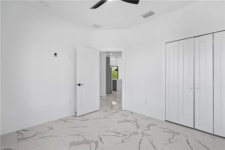 Interior room featuring large format tile flooring, white walls, and a black ceiling fan