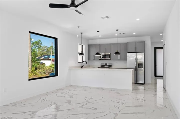 Modern kitchen featuring stainless steel appliances, grey cabinetry, a quartz countertop island with pendant lighting, and a matte black faucet