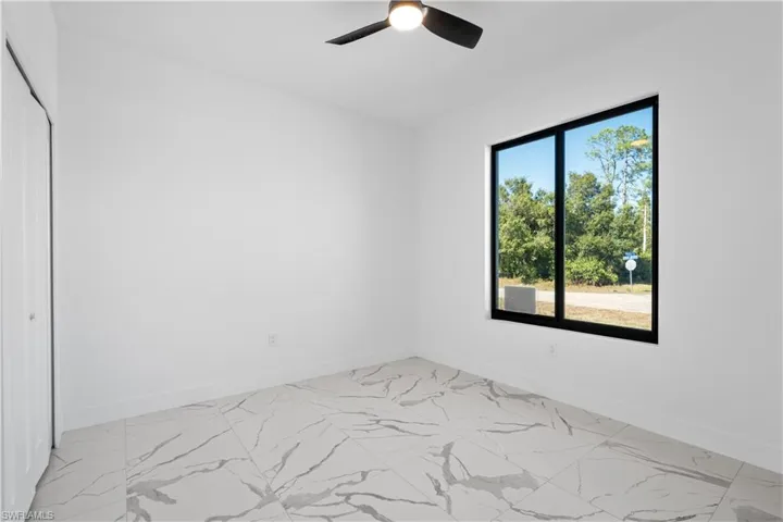 Room featuring light-toned walls, a single window with black trim, and a black ceiling fan