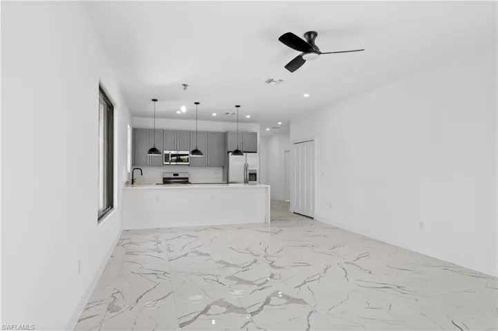 Open-concept living area featuring large format marble-look tile flooring, a contemporary ceiling fan, and recessed lighting