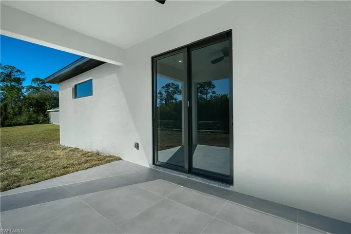 Covered patio featuring large format gray tile flooring and white stucco exterior