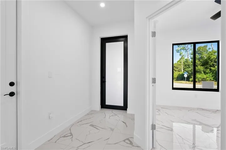 Foyer featuring large format tile flooring, a modern black-framed glass entry door, recessed lighting, and a white interior door with matte black hardware