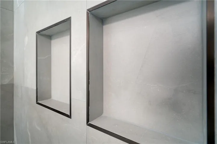 Recessed wall niches with dark trim detailing, integrated into large format wall tiles