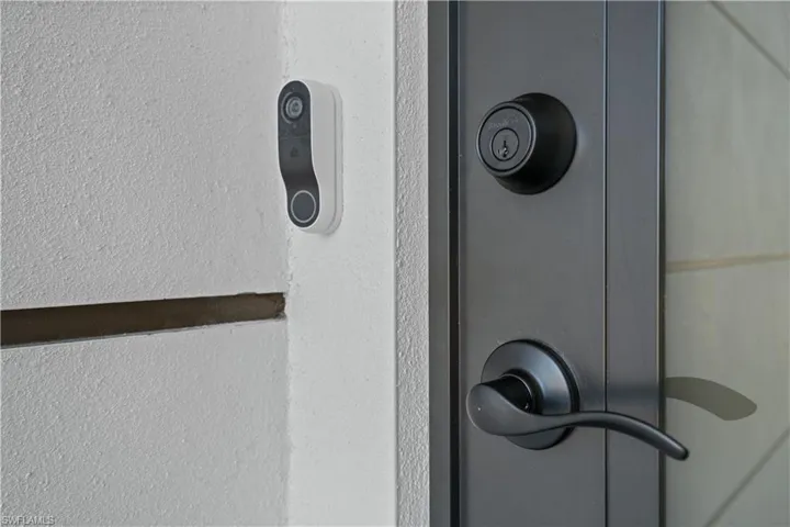 Exterior entry featuring a dark-finish door with matte black hardware, a deadbolt lock, and an integrated smart doorbell system