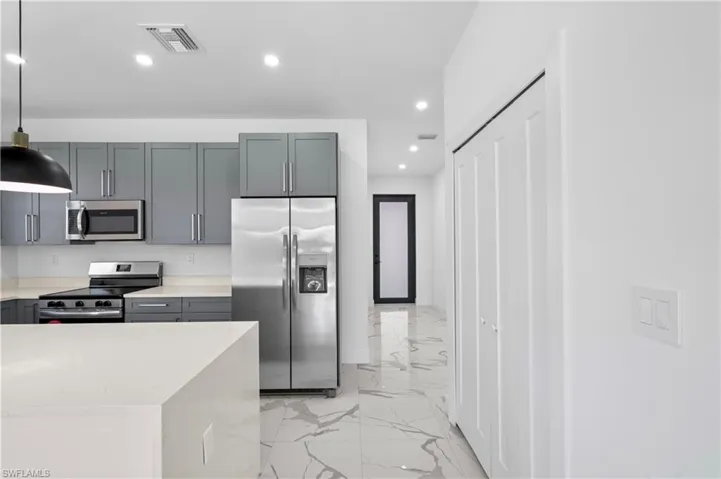 Contemporary kitchen featuring sleek gray cabinetry, stainless steel appliances, and light countertops