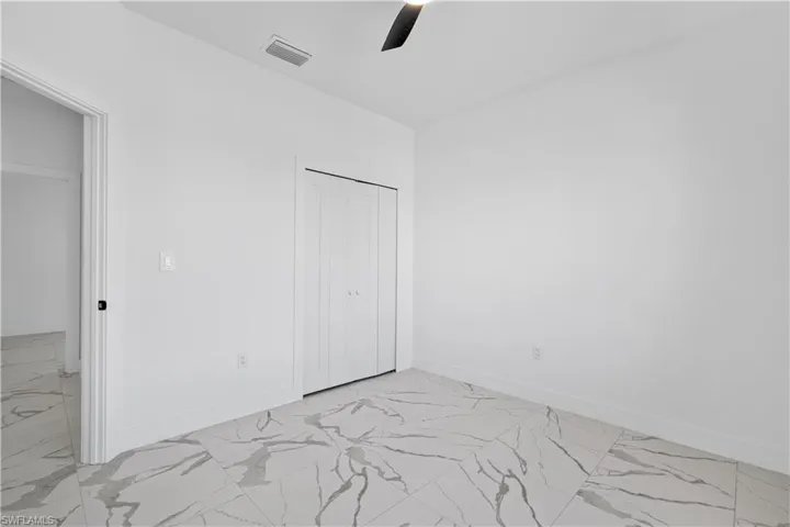 Room featuring large format marble-look tile flooring, white baseboards, and a contemporary ceiling fan