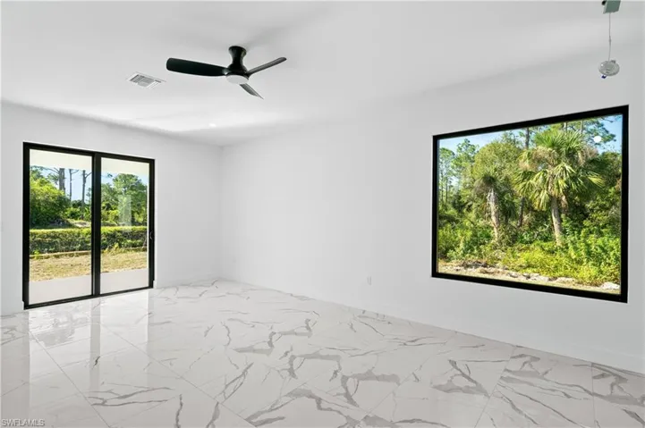 Spacious room featuring large format tile flooring and a modern ceiling fan