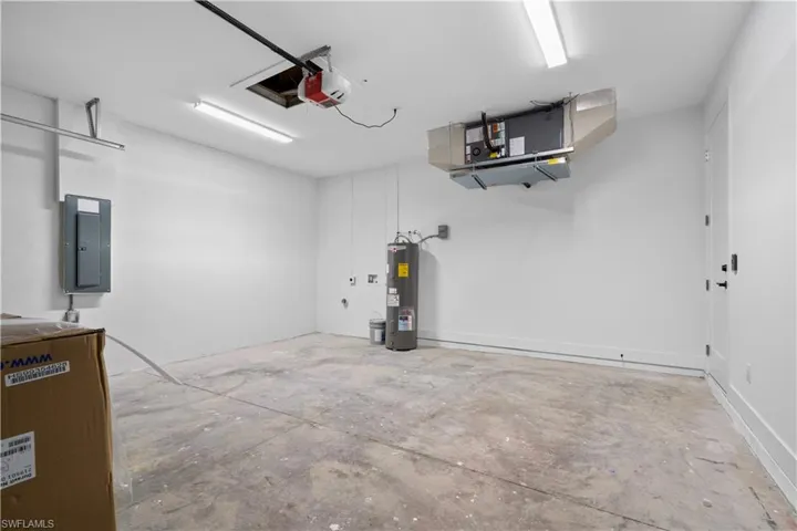 Spacious garage featuring a concrete floor, bright overhead lighting, and white painted walls