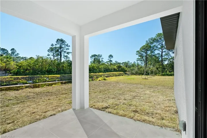 Covered patio with large format tile flooring and white pillars opening to an expansive yard