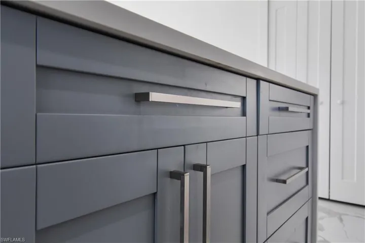 Custom cabinetry featuring a solid countertop, brushed nickel hardware, and paneled doors
