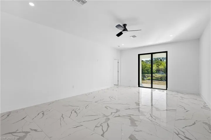 Spacious interior featuring large format marble-look tile flooring, a contemporary black ceiling fan, and recessed lighting