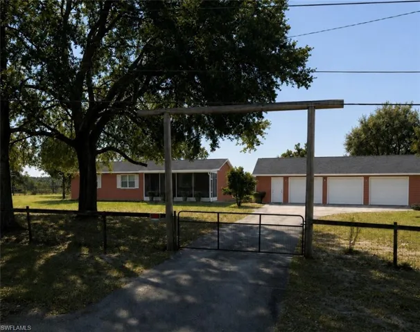 Gated entry to a ranch-style residence with an expansive screened porch and a detached four-car garage