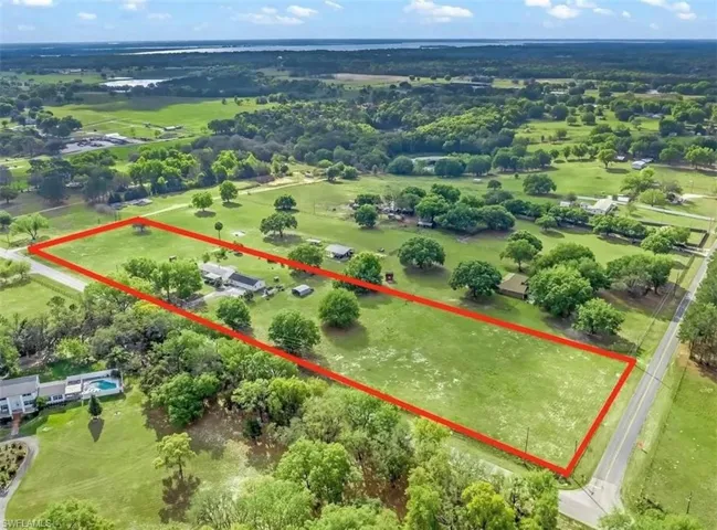 Expansive green acreage with a visible dwelling and mature trees