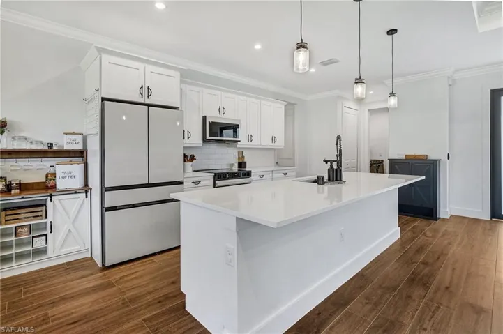 Kitchen featuring sink, a kitchen island, dark hardwood / wood-style floors, white refrigerator, and white cabinets