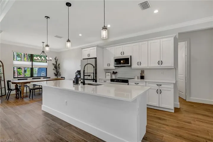 Kitchen featuring a center island with sink, white cabinets, hardwood / wood-style floors, and appliances with stainless steel finishes