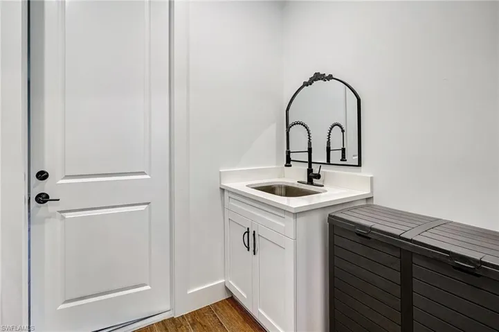 Laundry room with dark hardwood / wood-style flooring and sink