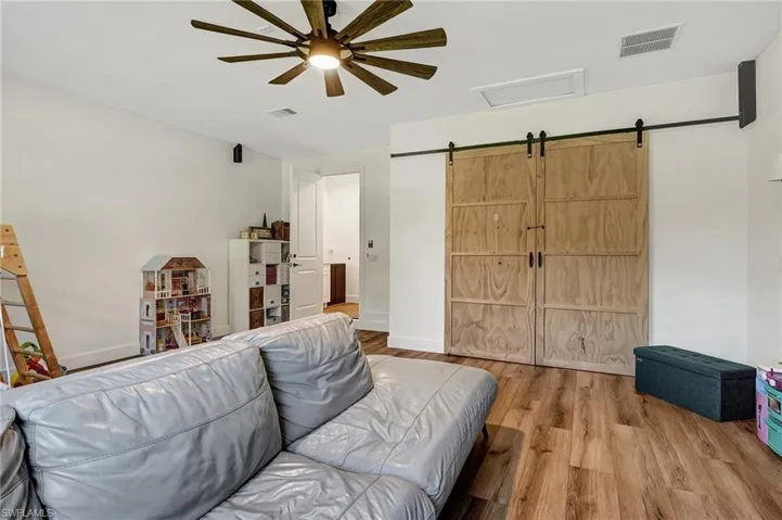 Living room with a barn door, ceiling fan, and hardwood / wood-style floors