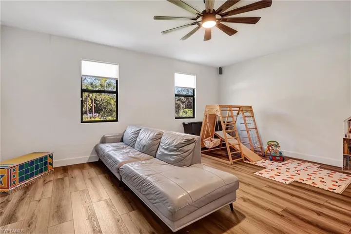 Living room featuring hardwood / wood-style flooring, ceiling fan, and a healthy amount of sunlight
