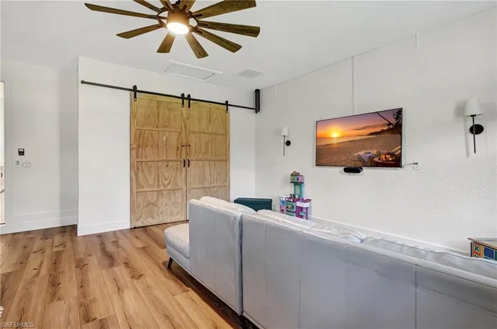 Living room with a barn door, light hardwood / wood-style floors, and ceiling fan