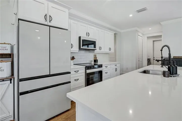 Kitchen featuring white cabinets, refrigerator, sink, light hardwood / wood-style flooring, and electric range oven